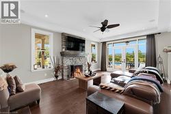 Living area with wood-type flooring, a stone fireplace, french doors, ceiling fan, and recessed lighting - 