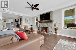 Living area featuring plenty of natural light, wood finished floors, a fireplace, a tray ceiling, and recessed lighting - 