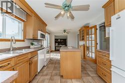Kitchen featuring a center island, white appliances, healthy amount of natural light, and ceiling fan - 