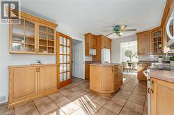 Kitchen featuring glass insert cabinets, white appliances, decorative backsplash, ceiling fan, and light countertops - 