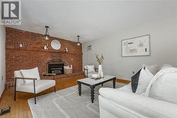 Living room featuring brick wall, hardwood / wood-style flooring, a fireplace, and an AC wall unit - 