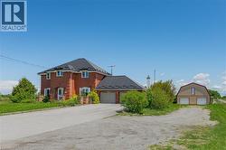 View of front of house featuring brick siding, an outbuilding, driveway, and a detached garage - 