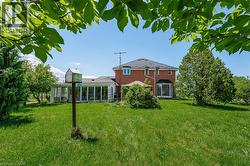 Rear view of property featuring a yard, a sunroom, and brick siding - 