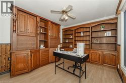 Office with built in features, a textured ceiling, ceiling fan, light wood-style floors, and wood walls - 