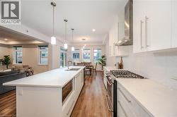 Kitchen featuring white cabinets, appliances with stainless steel finishes, open floor plan, light wood-style floors, and hanging light fixtures - 