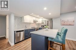 Kitchen with white cabinets, stainless steel appliances, blue cabinets, a kitchen breakfast bar, and a center island - 