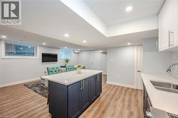 Kitchen featuring open floor plan, a kitchen island, light wood finished floors, recessed lighting, and light stone counters - 