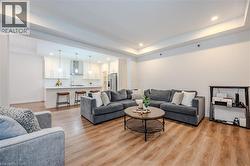 Living area featuring a raised ceiling, light wood finished floors, and recessed lighting - 