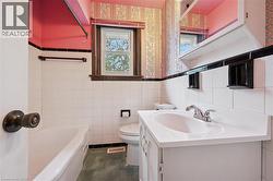 Full bathroom featuring a tub, tile walls, vanity, wallpapered walls, and wainscoting - 