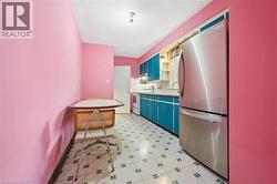 Kitchen with freestanding refrigerator, light countertops, blue cabinetry, white stove, and light floors - 