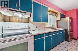 Kitchen featuring blue cabinetry, white range with electric stovetop, light countertops, and under cabinet range hood - 
