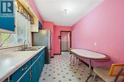 Kitchen with blue cabinets, light flooring, light countertops, and freestanding refrigerator - 