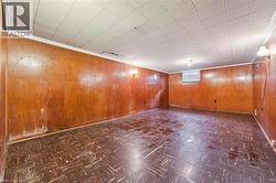 Basement with wooden walls, dark flooring, and crown molding - 