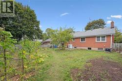 Rear view of house with a fenced backyard, brick siding, and a chimney - 
