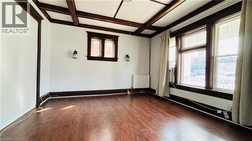 Empty room featuring dark wood-style flooring, beam ceiling, coffered ceiling, and radiator heating unit - 30 Regina Street N, Waterloo, ON - Indoor Photo Showing Other Room