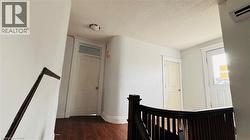 Hall featuring a textured ceiling, dark wood-style floors, an upstairs landing, and a wall unit AC - 