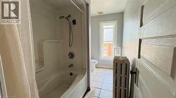 Bathroom featuring radiator, light tile patterned floors, and shower / washtub combination - 