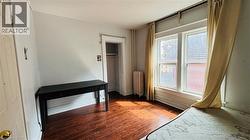 Unfurnished bedroom featuring dark wood finished floors and radiator heating unit - 