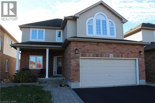 View of front of home featuring brick siding, covered porch, driveway, and a garage - 561 Thomas Slee Drive, Kitchener, ON - Outdoor
