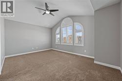 Spare room with visible vents, lofted ceiling, a ceiling fan, carpet floors, and baseboards - 