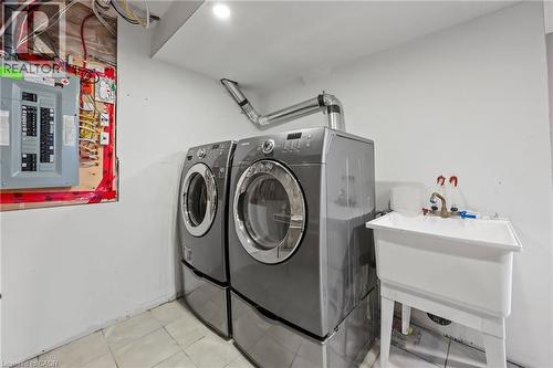 Clothes washing area featuring washing machine and clothes dryer, electric panel, laundry area, tile patterned floors, and a sink - 561 Thomas Slee Drive, Kitchener, ON - Indoor Photo Showing Laundry Room
