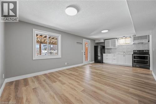 Kitchen featuring decorative backsplash, light wood finished floors, double oven range, and freestanding refrigerator - 561 Thomas Slee Drive, Kitchener, ON - Indoor Photo Showing Kitchen