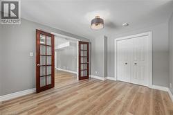Unfurnished bedroom featuring a closet, french doors, baseboards, and light wood-style floors - 