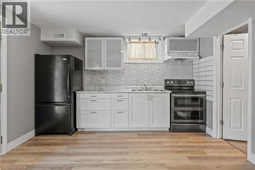 Kitchen featuring visible vents, range with two ovens, light wood-style flooring, freestanding refrigerator, and under cabinet range hood - 561 Thomas Slee Drive, Kitchener, ON - Indoor Photo Showing Kitchen