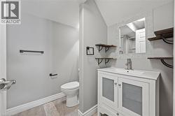 Bathroom with toilet, vanity, baseboards, and vaulted ceiling - 