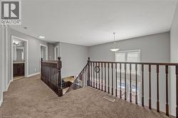 Hallway featuring baseboards, visible vents, carpet floors, a textured ceiling, and an upstairs landing - 