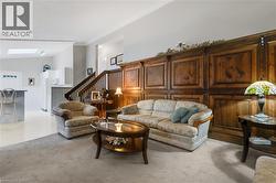 Living area featuring stairs, a skylight, and vaulted ceiling - 