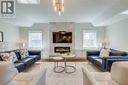 Living room featuring a high end fireplace, wood finished floors, and vaulted ceiling - 