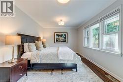 Bedroom featuring visible vents, ornamental molding, baseboards, and wood finished floors - 