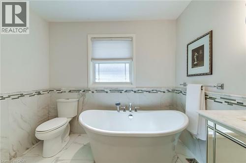 Bathroom with tile walls, a soaking tub, toilet, and marble finish floor - 4306 Lakeshore Road, Burlington, ON - Indoor Photo Showing Bathroom