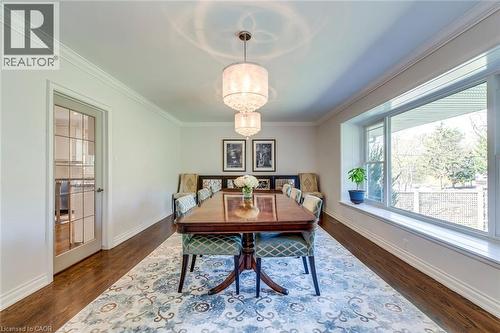 Dining area featuring baseboards, ornamental molding, a notable chandelier, and dark wood-style floors - 4306 Lakeshore Road, Burlington, ON - Indoor Photo Showing Dining Room