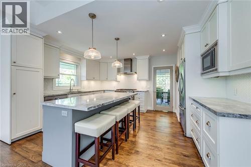 Kitchen with a sink, wall chimney exhaust hood, appliances with stainless steel finishes, and white cabinets - 4306 Lakeshore Road, Burlington, ON - Indoor Photo Showing Kitchen With Upgraded Kitchen