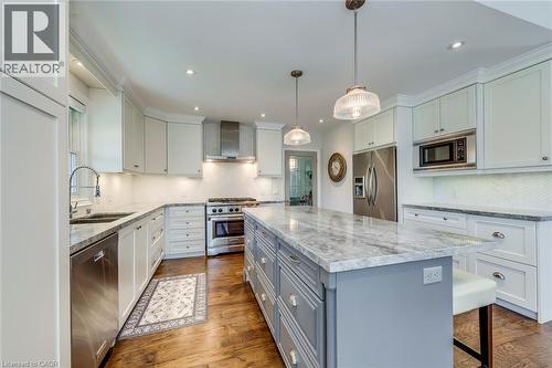 Kitchen featuring wall chimney range hood, a center island, a sink, backsplash, and stainless steel appliances - 4306 Lakeshore Road, Burlington, ON - Indoor Photo Showing Kitchen With Double Sink With Upgraded Kitchen