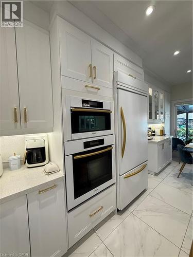 Kitchen with white cabinetry, light marble finish flooring, refrigerator, recessed lighting, and glass insert cabinets - 11 Donatello Court, Hamilton, ON - Indoor Photo Showing Kitchen