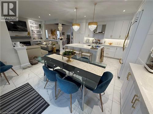 Kitchen with a center island with sink, light stone counters, white cabinetry, built in shelves, and wall chimney exhaust hood - 11 Donatello Court, Hamilton, ON - Indoor