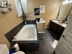 Full bathroom featuring a bath, double vanity, and dark tile patterned flooring - 