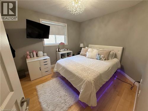 Bedroom featuring a textured ceiling, light wood-style flooring, and a chandelier - 11 Donatello Court, Hamilton, ON - Indoor Photo Showing Bedroom