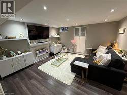 Living room featuring dark wood-type flooring, recessed lighting, and a stone fireplace - 