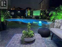 Pool at night featuring an outdoor living space, a patio, and a fenced backyard - 
