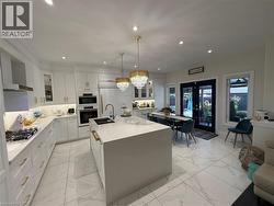 Kitchen featuring glass insert cabinets, decorative light fixtures, white cabinets, light stone counters, and french doors - 