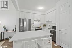 Kitchen with appliances with stainless steel finishes, light countertops, white cabinets, a breakfast bar area, and a kitchen island - 