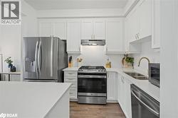 Kitchen with stainless steel appliances, white cabinets, and under cabinet range hood - 