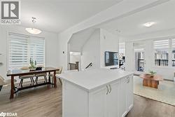 Kitchen featuring white cabinets, light wood-type flooring, decorative light fixtures, and a center island - 
