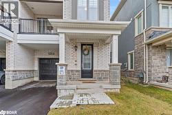Entrance to property featuring driveway, an attached garage, brick siding, and stucco siding - 
