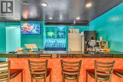 Indoor wet bar with dark countertops and recessed lighting - 