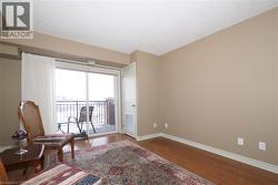 Living room with classic hardwood flooring looking toward patio doors opening up to covered balcony. - 